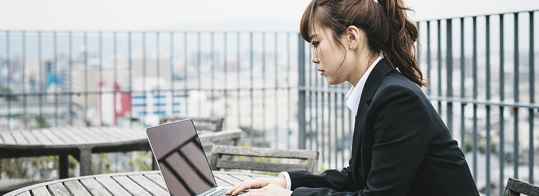 سيدة تعيش في مدينة كيوتو اليابانية تعمل على كمبيوتر محمول في الخارج